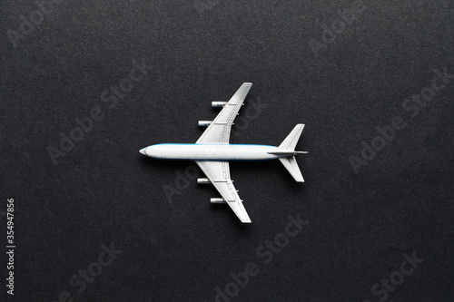 Flight and air transport concept - toy airplane on black background top view.