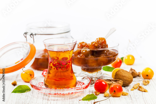 Azerbaijani Tea Culture Armudu Tea Glass and Cherry Jam with Nuts. Azerbaijani Cuisine White Cherry Preserves. Selective focus.