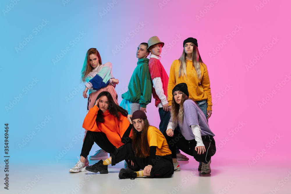 Φωτογραφία Group of dancers, boys and girls dancing hip-hop in stylish clothes on colorful gradient background at dance hall in neon