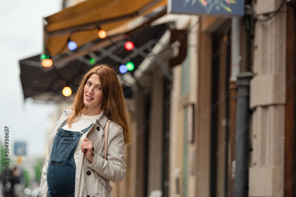Beautiful young pregnant woman wearing casual clothes walking through the city streets. concept of motherhood and pregnancy. street portrait among cars close up view. Beautiful young pregnant woman wearing casual clothes walking through the city streets. concept of motherhood and pregnancy. street portrait among cars close up view.