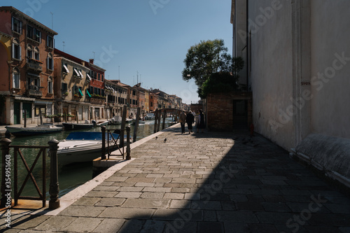 People are walking along the Cannaregio canal in Venice, Italy.