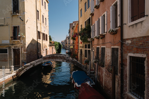 Empty canal of Cannaregio district, only two people are sitting on the bridge in Venice, Italy.