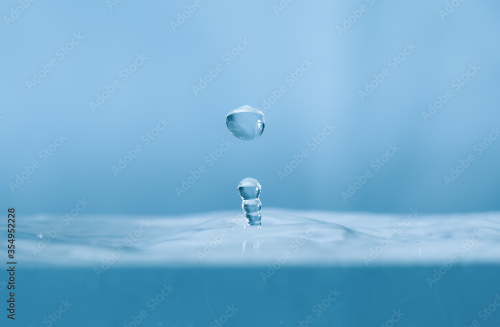 Water drops splash and circle reflextion background.Close up rain drops falling into the water and ripples of light blue. Water drops splash and circle reflextion background.Close up rain drops falling into the water and ripples of light blue.