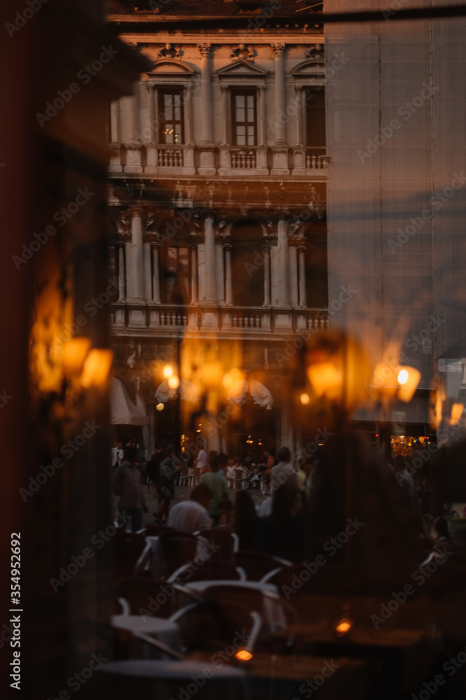 View through the window to the restaurant of Venice and the people reflected in the window from the street, Italy.