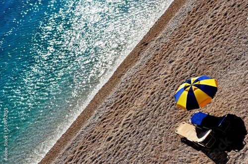 loungers on the beach of Porto Katsiki on Lefkada Islandб beautiful seascape background, a yellow-blue umbrella. sea view, social distance on the beach photo