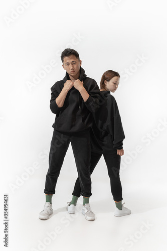 Inclusion. Trendy fashionable couple isolated on white studio background. Stylish woman and man posing in basic minimal stylish clothes equally suitable for both. Concept of equality, inclusive.