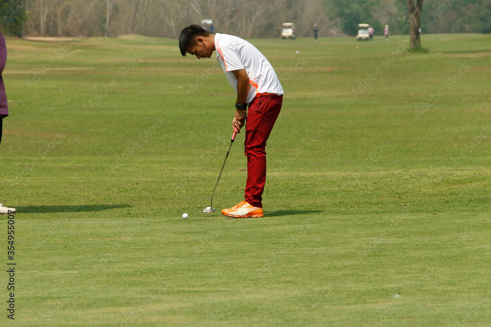 Obraz premium Golfer playing golf in the evening golf course, on sun set evening time. Man playing golf on a golf course in the sunset background