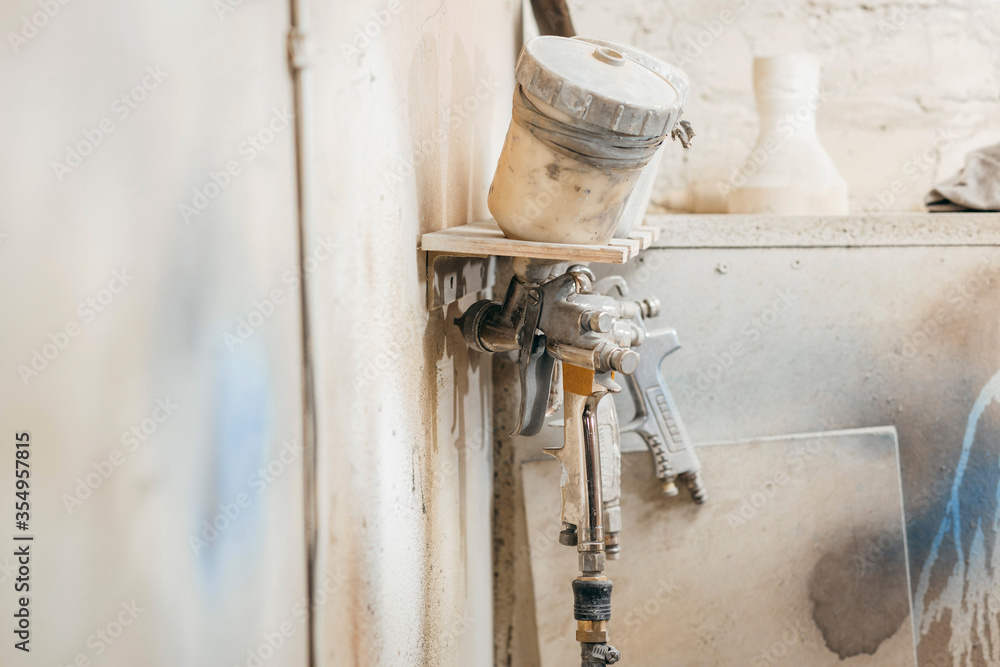 View of the paint shop of carpentry.  Three spray guns hang on the wall, close up view