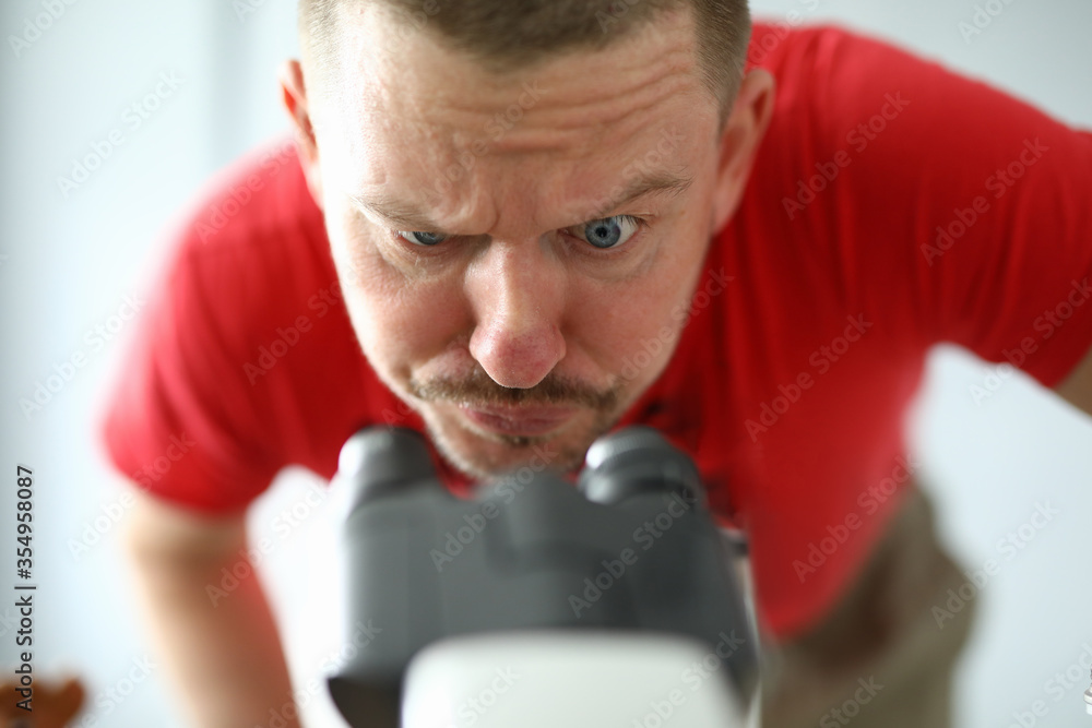 Pensive man attentively looks through microscope Pensive man attentively looks through microscope