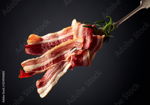 Slices of tasty fried bacon garnished with rosemary.