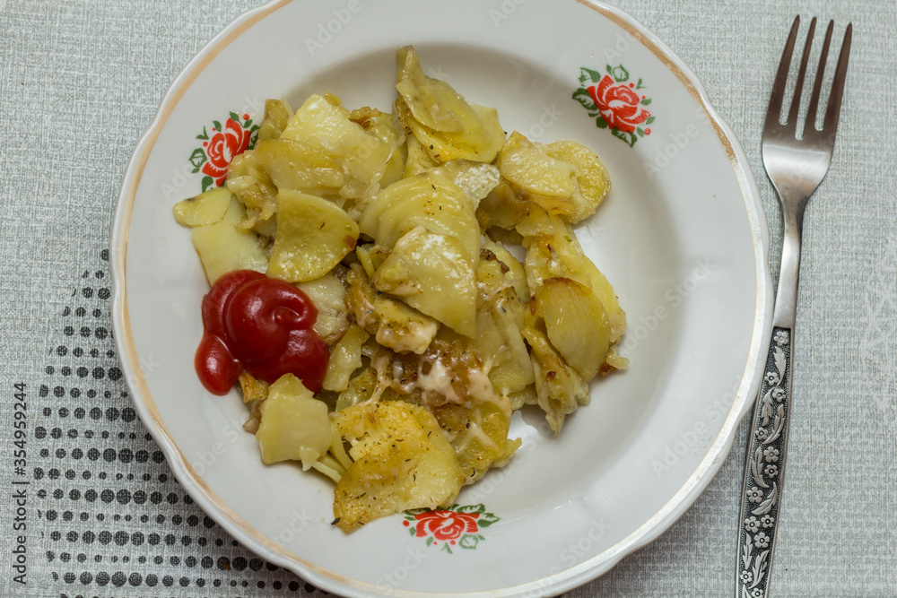 fried potatoes with onions, garlic, bacon, seasonings, ketchup and parmesan in a plate.