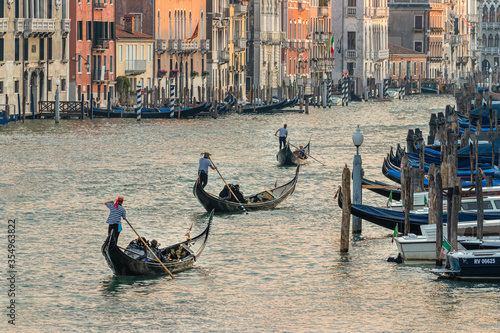 Three gondoliers navigate the Grand Canal at sunset in Venice Italy photo