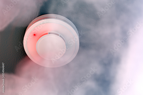 Schilderij op canvas Dire alarm smoke detector with red LED indicator on ceiling