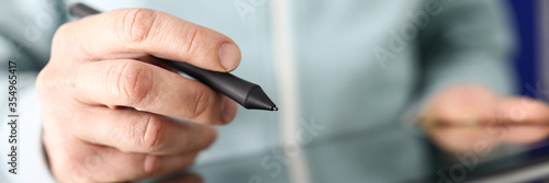 Male hand holding stylus going to make notes