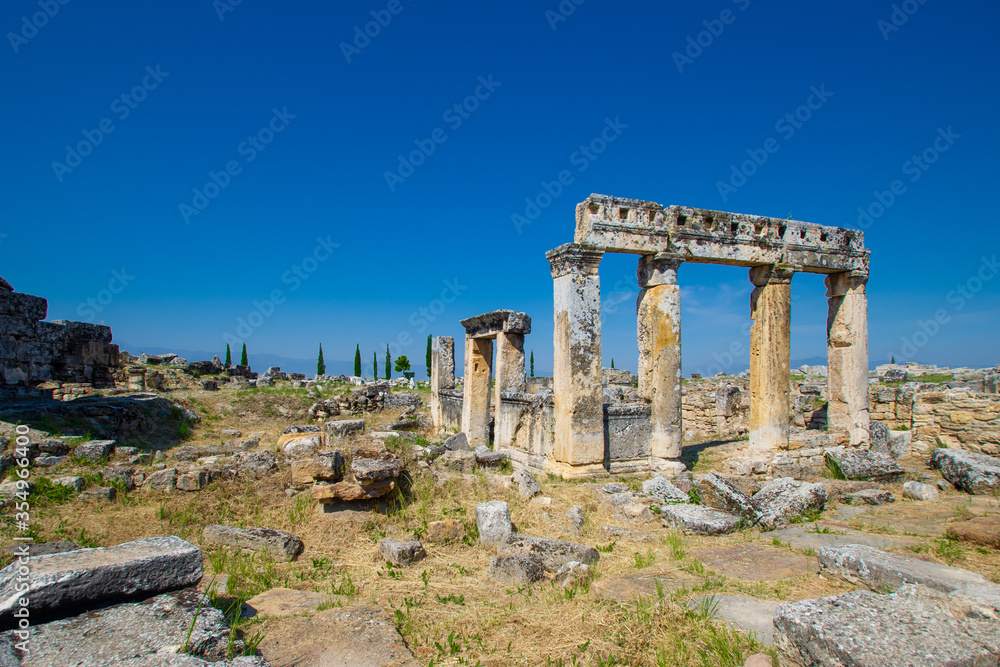 Ruins of ancient colonnade & buildings on Frontinus street in antique city Hierapolis, Pamukkale, Turkey. It was one of main streets in city. Hierapolis included in UNESCO World Heritage List