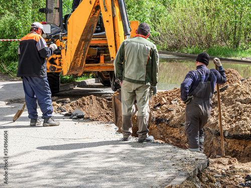 An excavator and three diggers dig a trench