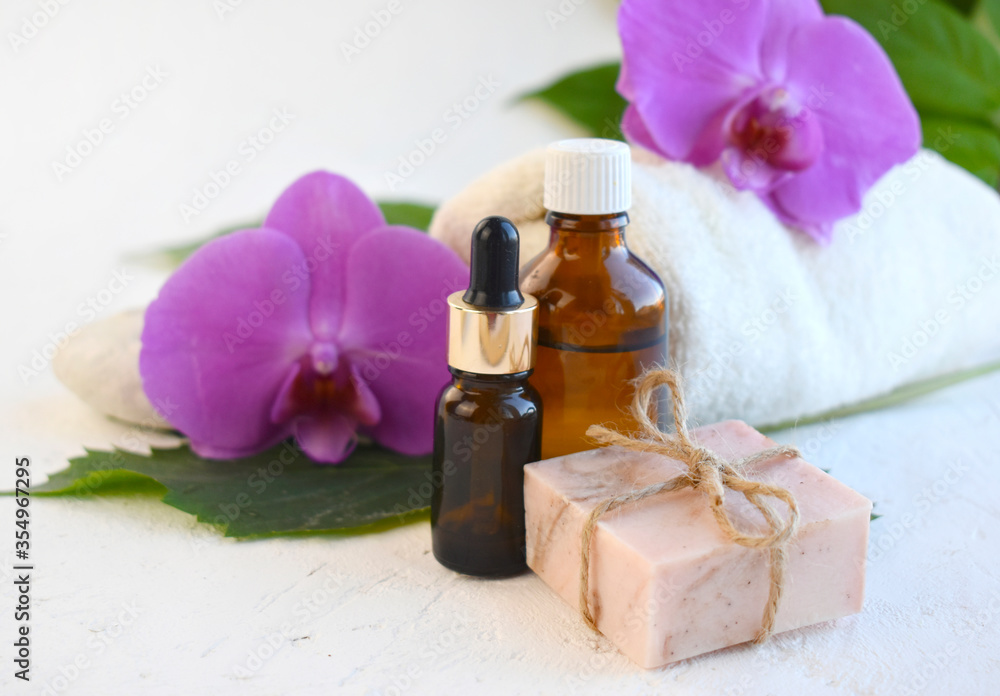 Spa aromatherapy bathe still life composition. Essential oil bottle, dropper, soap bar and orchid over light background. Organic cosmetic or herbal medicine concept. Tropical relax. Wellness Spa aromatherapy bathe still life composition. Essential oil bottle, dropper, soap bar and orchid over light background. Organic cosmetic or herbal medicine concept. Tropical relax. Wellness