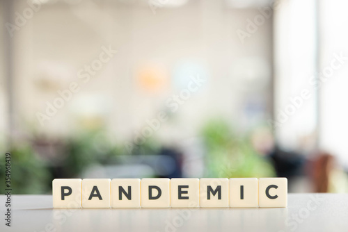 white cubes with pandemic lettering on white desk, covid-19 concept