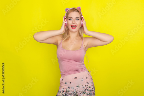 Blonde woman in summer clothing wearing pink headphones