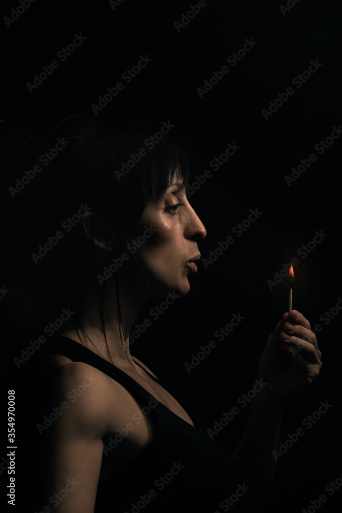 Fototapeta premium Mujer apagando llama en la oscuridad