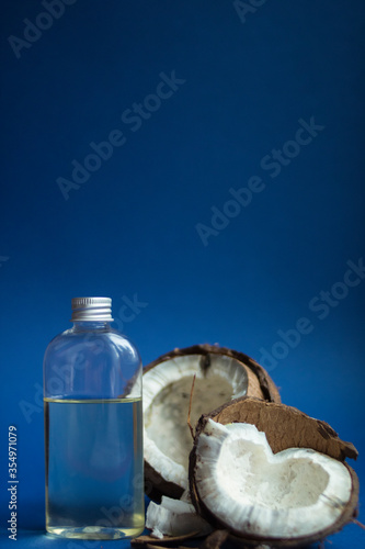 Beautiful open coconut with  liquid transparent melted coconut oil on a blue background