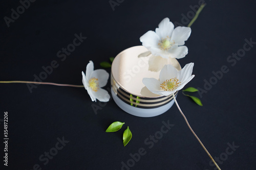 cosmetic jar with white flowers on a black background   