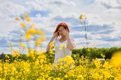 Girl cries and rubs her eyes due to allergy to pollen photo