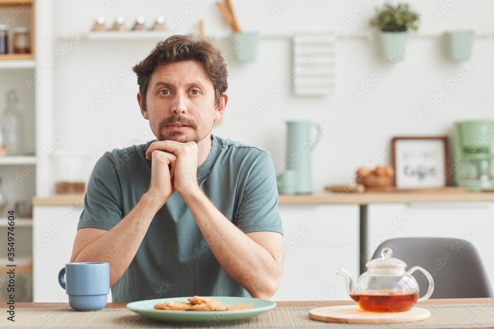 Portrait of young man sitting at the table and looking at camera during his breakfast at home Portrait of young man sitting at the table and looking at camera during his breakfast at home