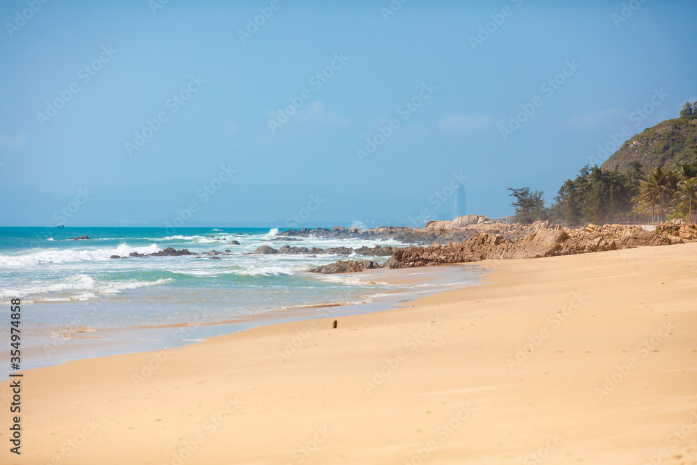 Natural background of turquoise colored sea with foamy waves and sandy beach with huge stones. Amazing blue sky during summer days. Concept of adventure and travelling. Natural background of turquoise colored sea with foamy waves and sandy beach with huge stones. Amazing blue sky during summer days. Concept of adventure and travelling.