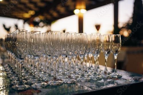 Many empty champagne glasses stand on table at party