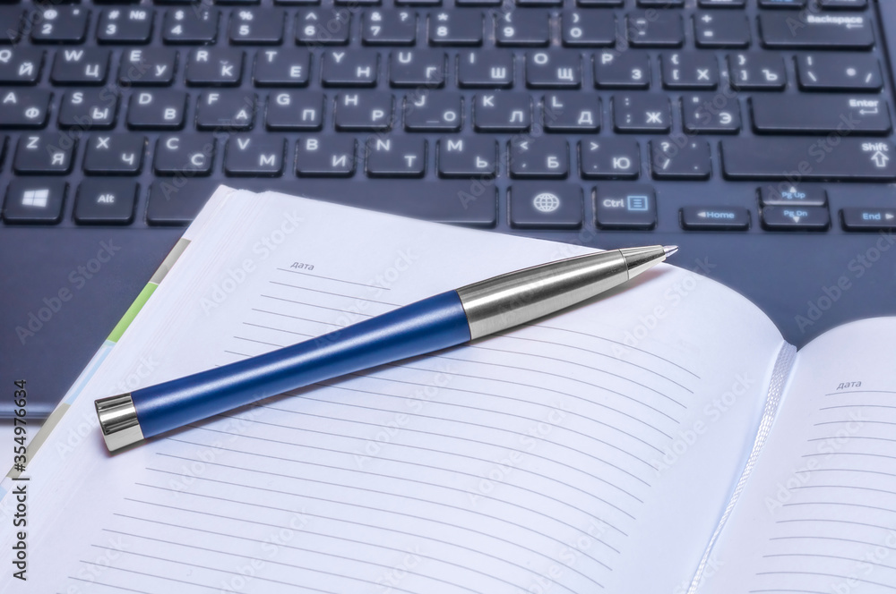 Notebook and pen on the black keyboard. Close up. Notebook and pen on the black keyboard. Close up.