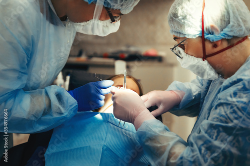 Fotografi Dentist And Assistant Treat Teeth Of Little Girl