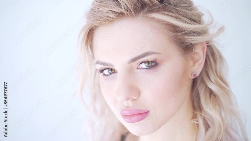 Portrait of close up of young sexy sporty blonde girl. Athlete with green eye makeup and pink lipstick on her lips. Sexually bites his lips. He poses and looks at the camera. Female is a fitness Portrait of close up of young sexy sporty blonde girl. Athlete with green eye makeup and pink lipstick on her lips. Sexually bites his lips. He poses and looks at the camera. Female is a fitness
