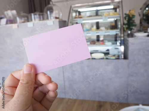 Holding a pink paper with coffee shop background