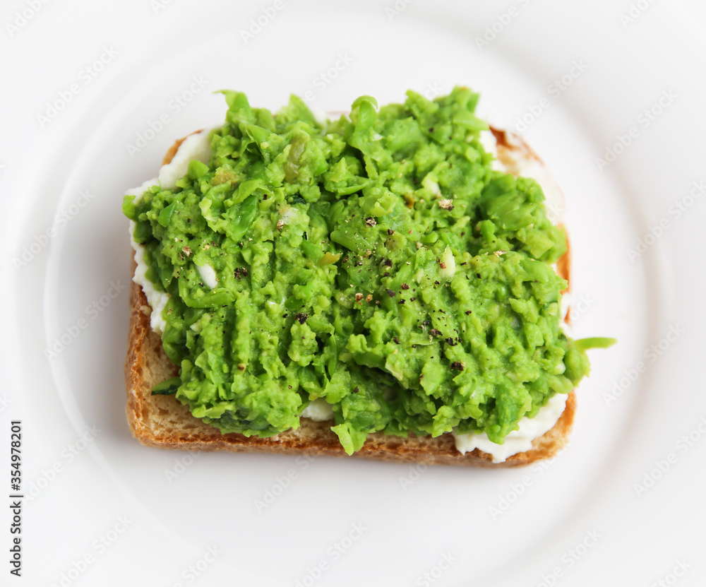 Classic english pea and ricotta toast on white plate Classic english pea and ricotta toast on white plate