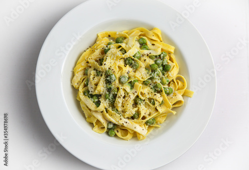 Tagliatelli con Limone e Piselli on white plate, Traditional italian pasta with lemon and peas.