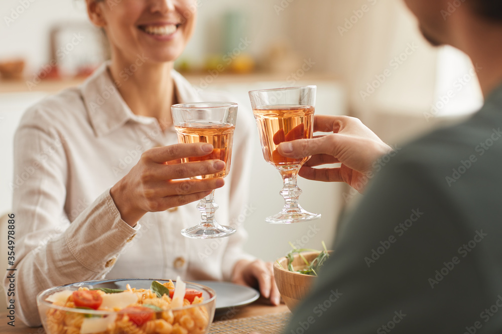 Close-up of young couple having dinner together at the table and toasting with glasses of wine Close-up of young couple having dinner together at the table and toasting with glasses of wine