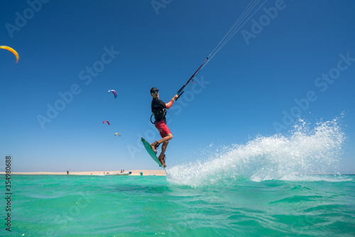 kiter does a difficult trick on a background of transparent water and blue sky © ohrim