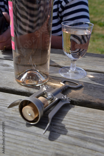 Steel bottle opener with cork still in in front of wine bottle