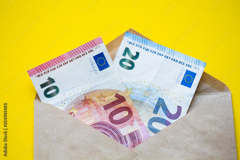 Obraz premium Euro banknotes in a white envelope on a wooden background. Cash savings