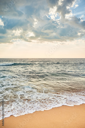 Tropical beach with horizon over ocean water at sunset.