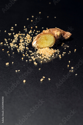 Ginger root with brown sugar on black background