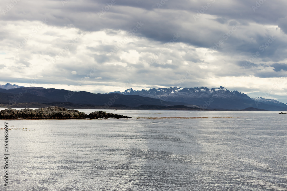Small stone island in the Beagle Channel near Ushuaia (Argentina) with mountains in the background