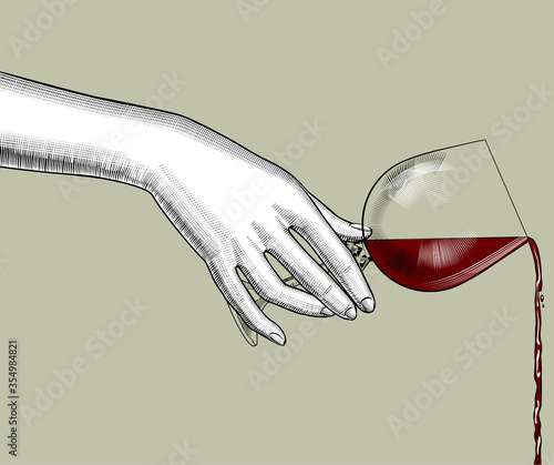 Female hand pours wine from a glass