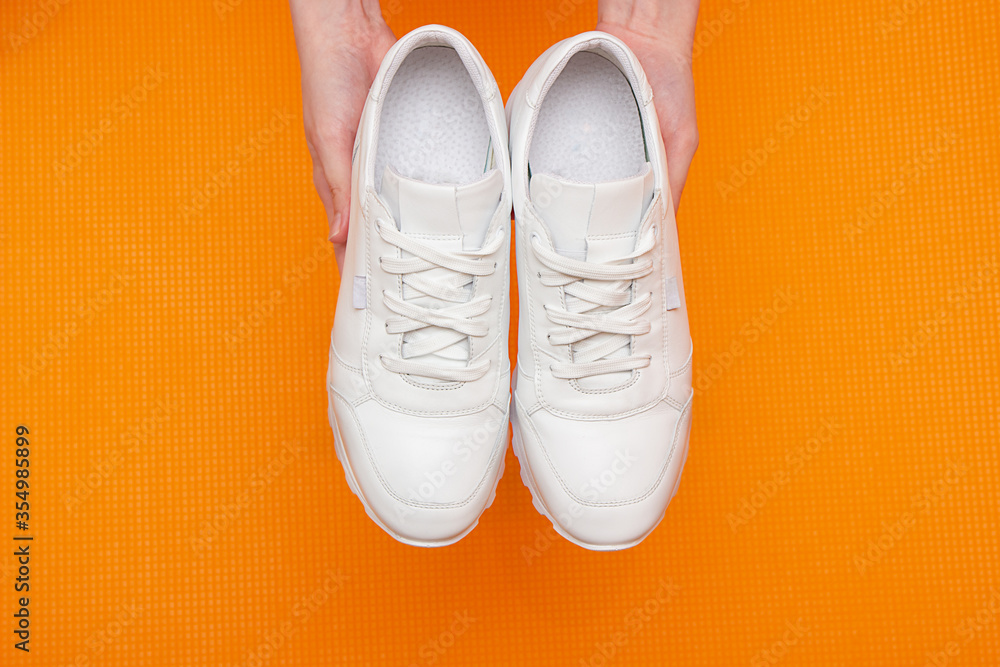 Fitness concept with white sneakers in hands, on a yellow background. view from above. Copy space Fitness concept with white sneakers in hands, on a yellow background. view from above. Copy space