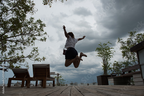 Happy woman jump high in the cloudy morning.