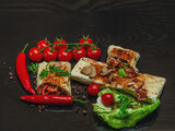 Shawarma cut in half with chicken meat on a black background. View from above. Cheese, red pepper parsley. Street Food, Fast Food, Oriental Food