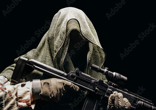 Fototapeta Fully equipped soldier in tactical net scarf with sniper rifle.