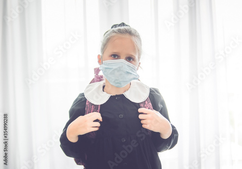 Portrait of little girl with apron and bag ready to go back to school with mask © Fabbbio7