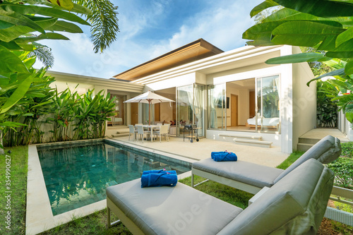 Interior and exterior design of luxury pool villa, house, home feature swimming pool, sunbed, blue beach towels and garden landscape © korakoch